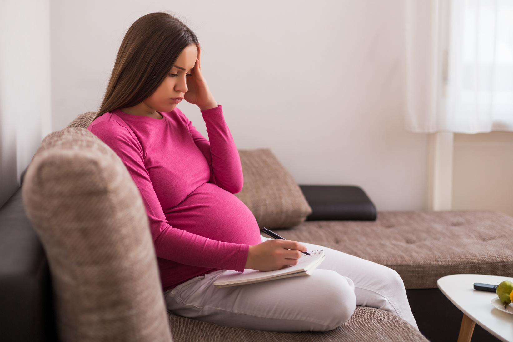 Worried pregnant woman writing to do list