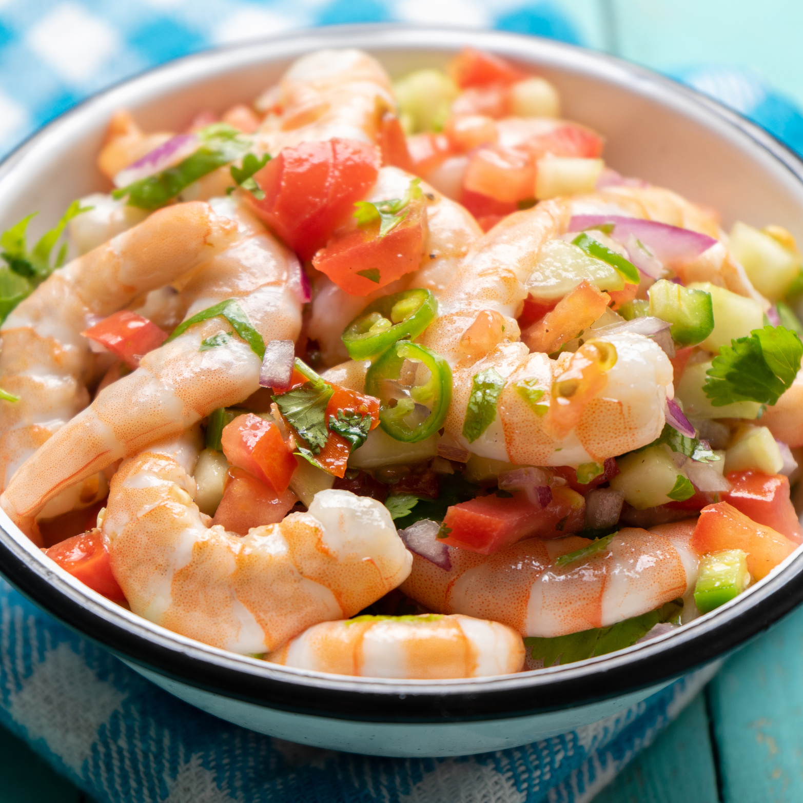 Mexican shrimp ceviche with tomato and serrano pepper on turquoise background