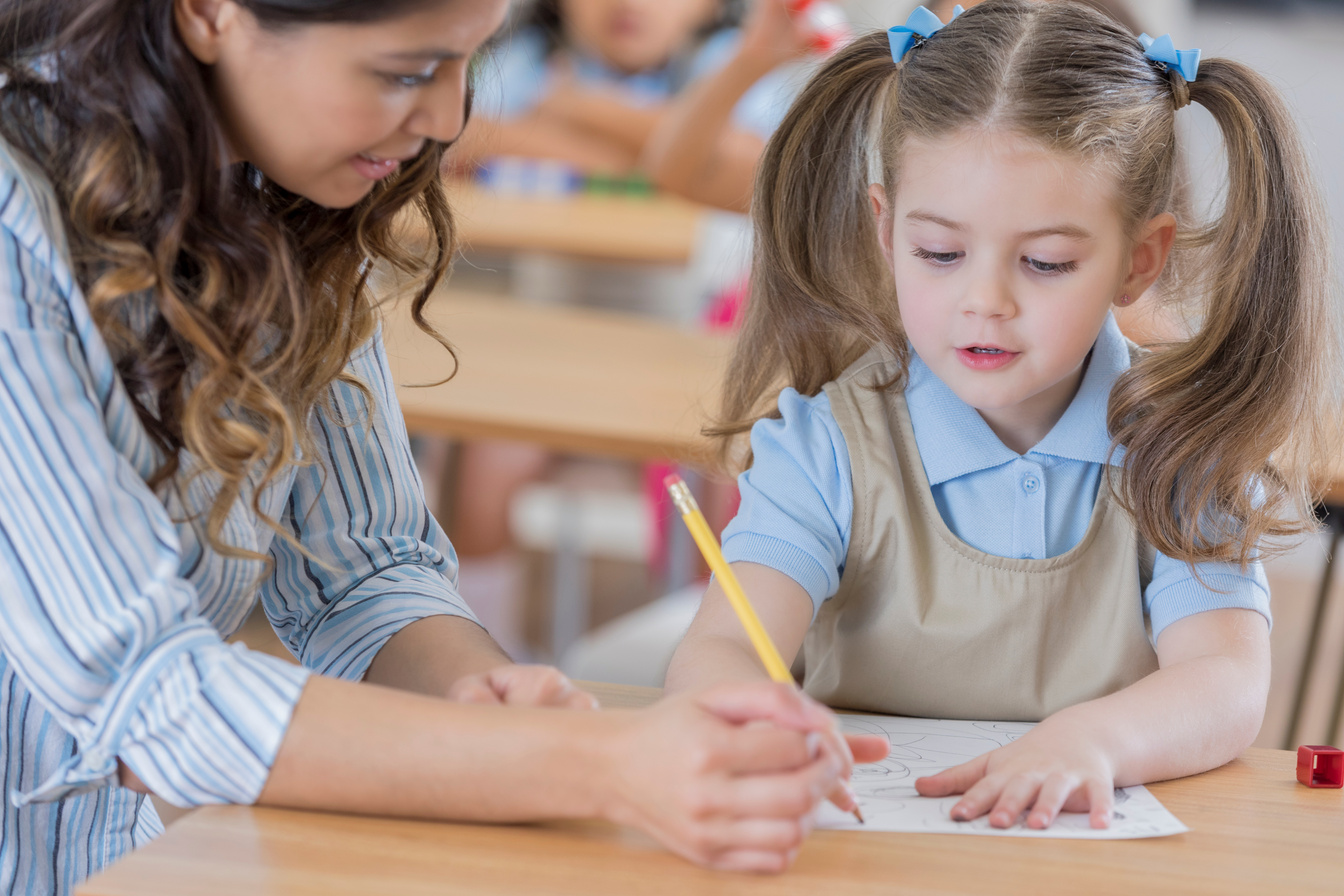 Little girl works on worksheet in kindergarten class