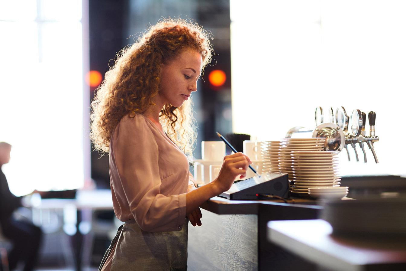 Pensive waitress adding order in restaurant POS